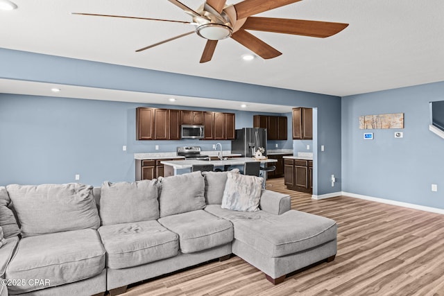 living area with light wood-style floors, recessed lighting, baseboards, and a ceiling fan