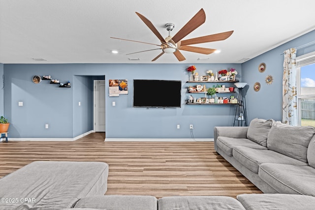 living area featuring baseboards, visible vents, a ceiling fan, and wood finished floors