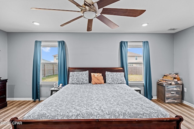 bedroom featuring multiple windows, visible vents, baseboards, and wood finished floors