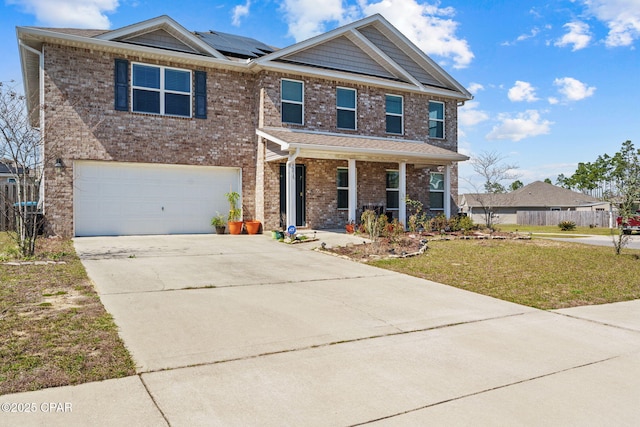 view of front of home featuring an attached garage, brick siding, concrete driveway, roof mounted solar panels, and a front yard