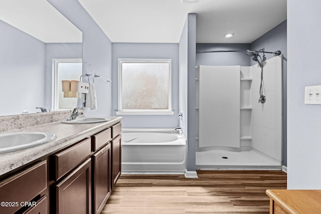 bathroom with a garden tub, walk in shower, a sink, and wood finished floors