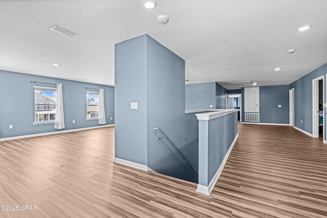 corridor featuring visible vents, wood finished floors, and an upstairs landing