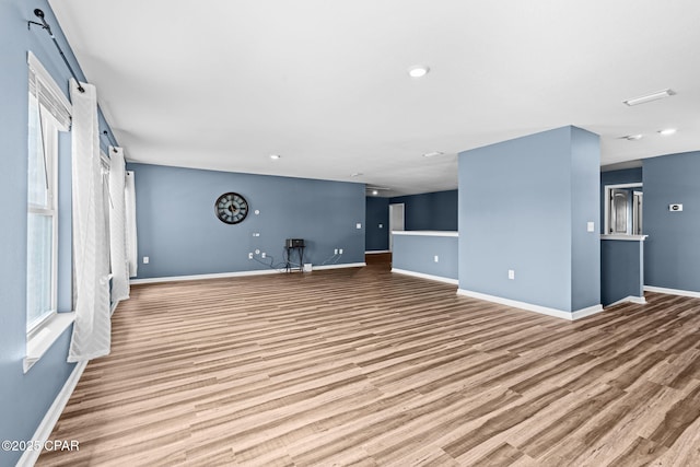 unfurnished living room with baseboards and wood finished floors