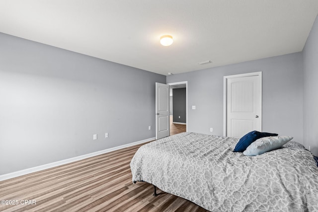 bedroom with wood finished floors, visible vents, and baseboards