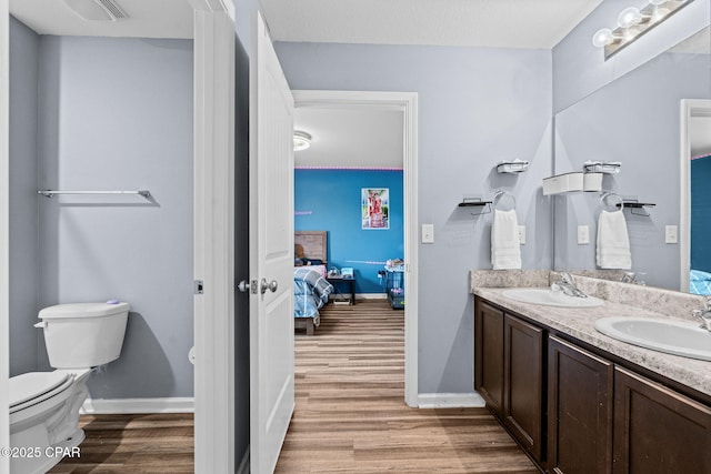 ensuite bathroom featuring ensuite bath, a sink, and wood finished floors