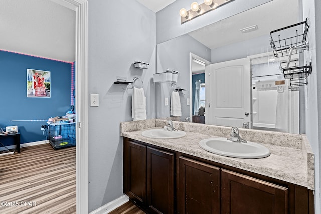 bathroom featuring double vanity, a sink, visible vents, and baseboards