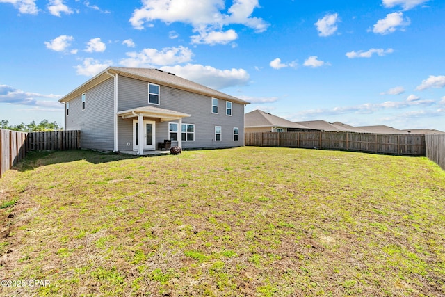 rear view of house with a fenced backyard and a lawn