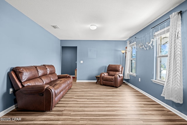 living room with wood finished floors, visible vents, and baseboards