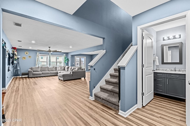 interior space with stairway, baseboards, visible vents, and light wood finished floors