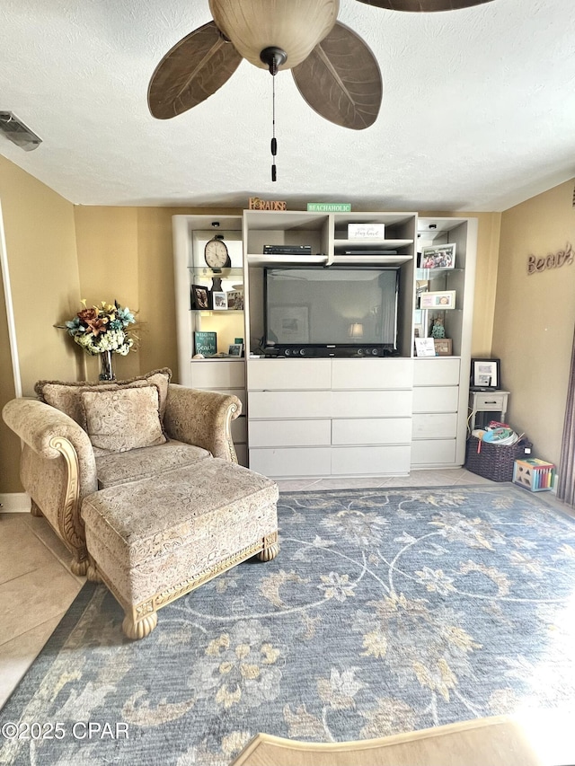 living room with a ceiling fan, visible vents, a textured ceiling, and tile patterned floors