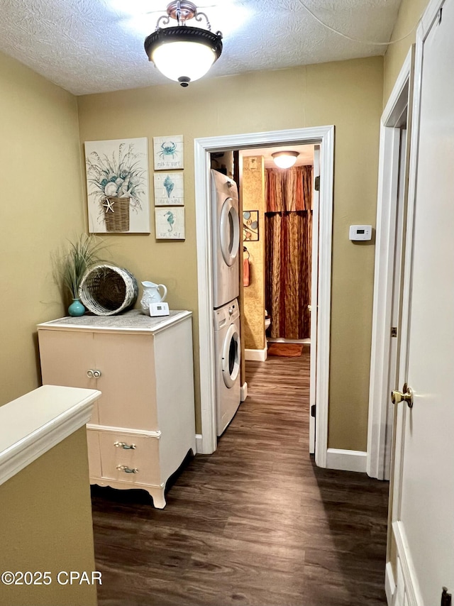 laundry area featuring stacked washing maching and dryer, dark wood-style floors, laundry area, and a textured ceiling