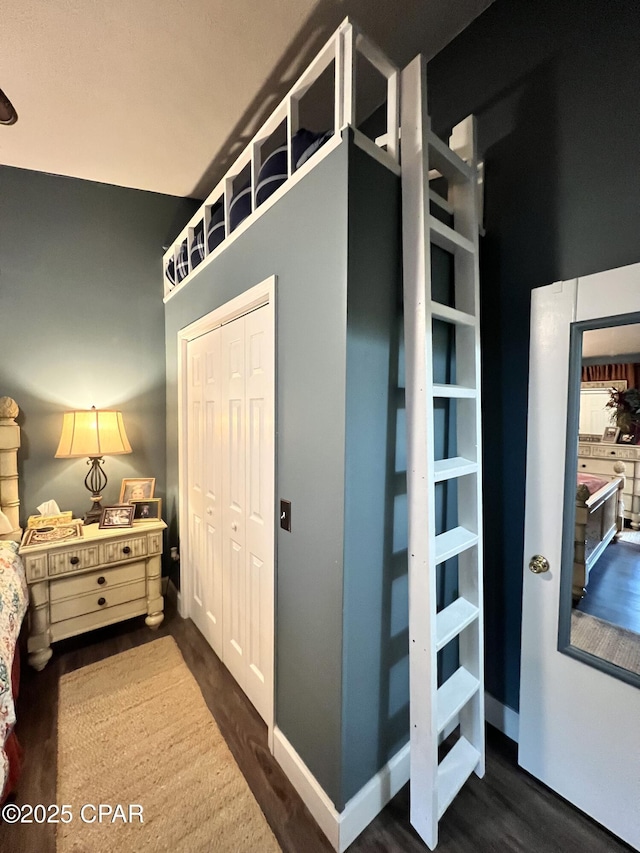 unfurnished bedroom with dark wood-type flooring, a closet, and baseboards