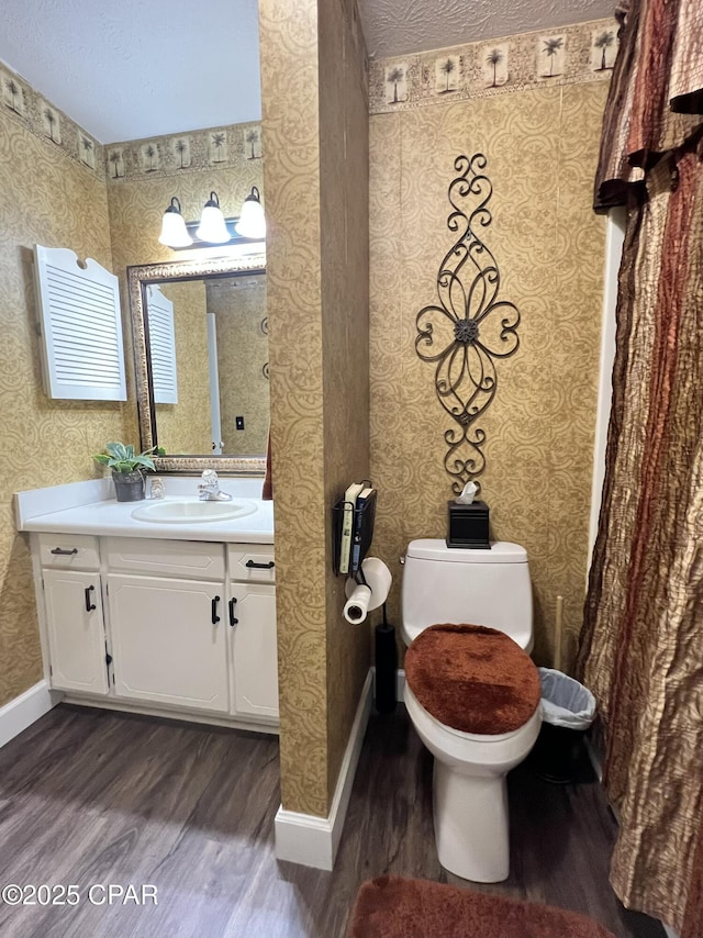 bathroom featuring wood finished floors, toilet, and wallpapered walls