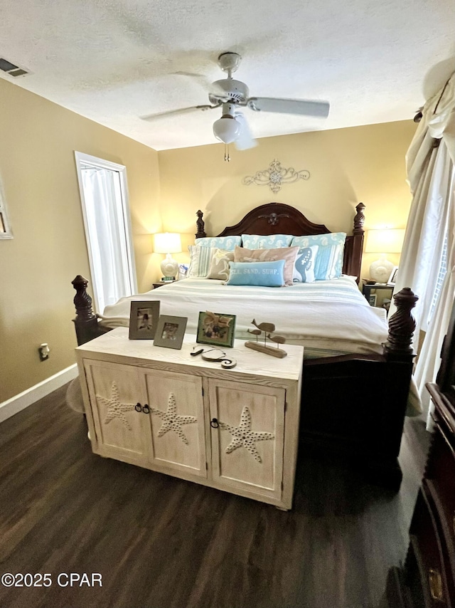 bedroom with a textured ceiling, a ceiling fan, visible vents, baseboards, and dark wood-style floors