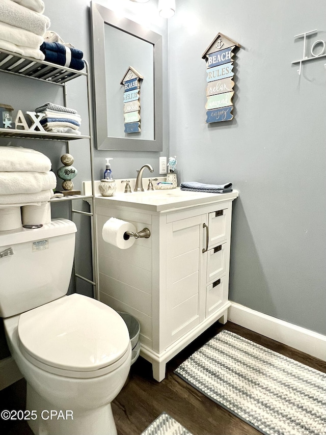 bathroom with baseboards, vanity, toilet, and wood finished floors