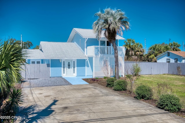 view of front of home with a shingled roof, a front yard, and fence