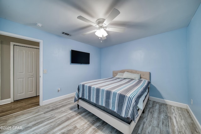 bedroom with a ceiling fan, baseboards, visible vents, and wood finished floors