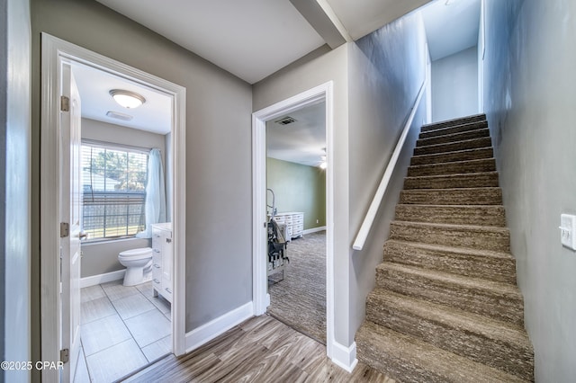 staircase with visible vents, baseboards, and wood finished floors