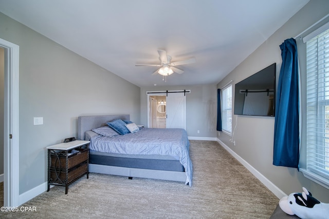 carpeted bedroom featuring a ceiling fan, connected bathroom, baseboards, and a barn door