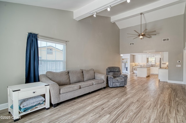 living area with baseboards, visible vents, ceiling fan, light wood-style floors, and beam ceiling