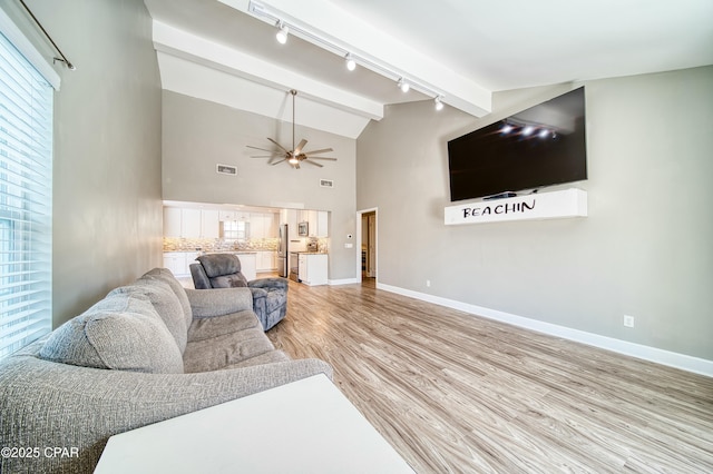 living room featuring light wood-style floors, a ceiling fan, baseboards, and beam ceiling