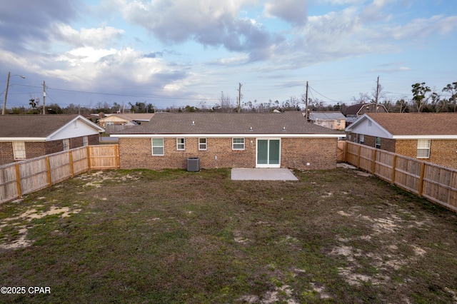 back of property with a patio, brick siding, central AC, and a fenced backyard