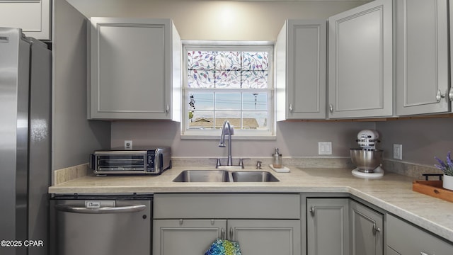 kitchen with a toaster, appliances with stainless steel finishes, light countertops, and a sink