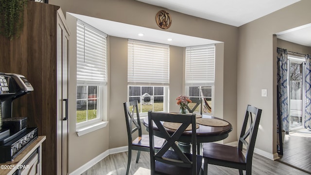 dining space with light wood-style flooring and baseboards