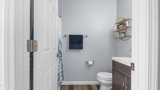 bathroom featuring toilet, vanity, wood finished floors, a shower with curtain, and baseboards