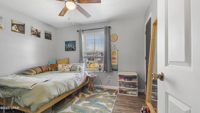 bedroom with a ceiling fan, a textured ceiling, baseboards, and wood finished floors