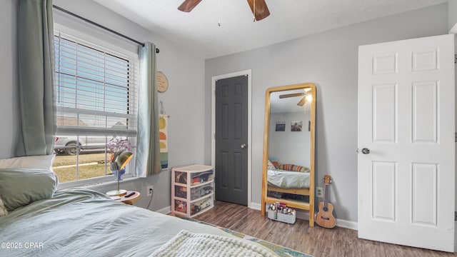 bedroom featuring a ceiling fan, baseboards, and wood finished floors