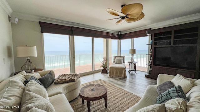 living room featuring a water view, light wood-style flooring, and crown molding