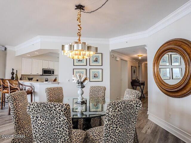 hall featuring baseboards, visible vents, wood finished floors, and ornamental molding