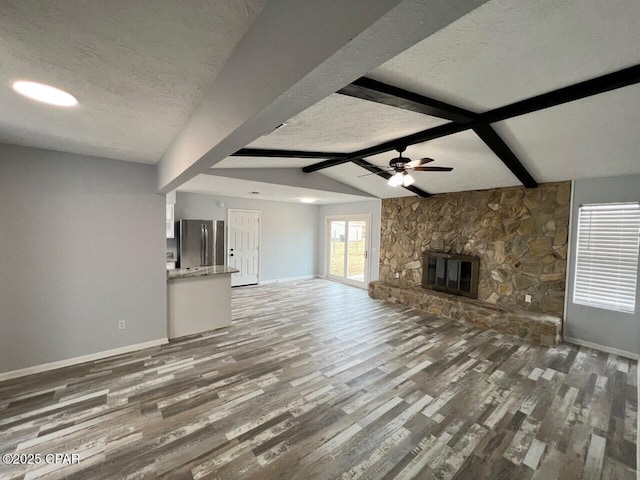 unfurnished living room featuring a fireplace, a textured ceiling, and wood finished floors