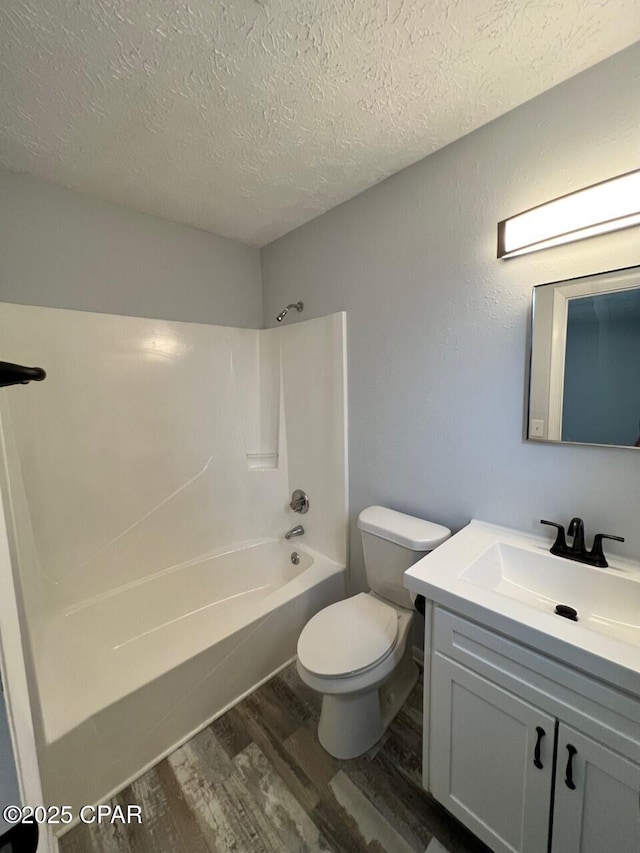 bathroom featuring toilet, a textured ceiling, wood finished floors, shower / bath combination, and vanity