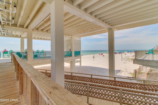 wooden terrace featuring a water view and a beach view
