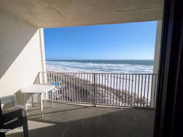 balcony featuring a view of the beach and a water view