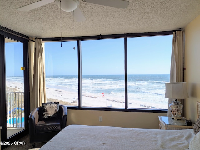 bedroom featuring a ceiling fan, a water view, and a textured ceiling