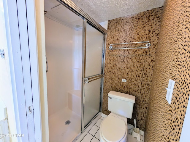 bathroom with a textured ceiling, toilet, tile walls, tile patterned floors, and a stall shower