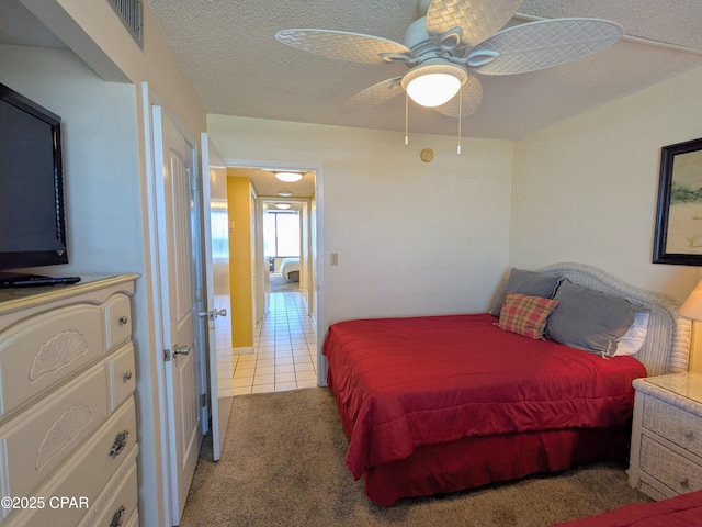 bedroom with carpet, ceiling fan, a textured ceiling, and tile patterned floors