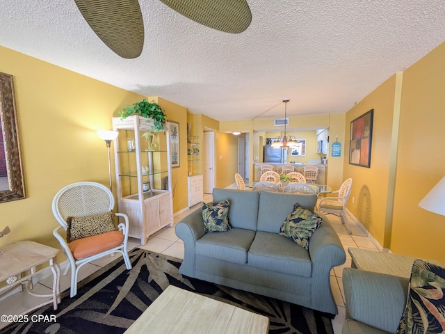 living area with light tile patterned floors, baseboards, a chandelier, and a textured ceiling