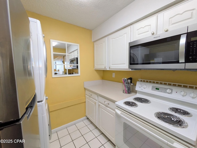 kitchen with a textured ceiling, light countertops, appliances with stainless steel finishes, and white cabinetry