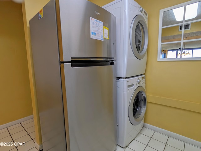 clothes washing area with laundry area, light tile patterned floors, visible vents, and stacked washer / dryer