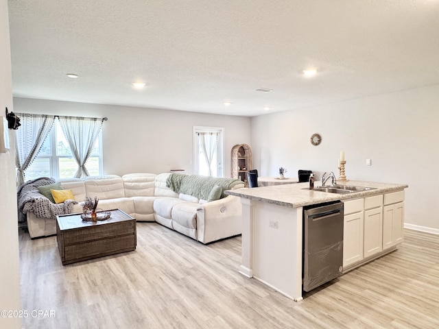 kitchen with light wood finished floors, open floor plan, dishwasher, and a sink