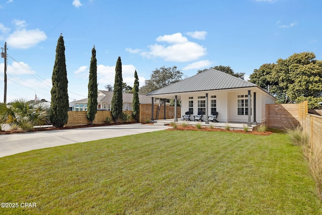 view of front of property with a patio area, metal roof, fence, driveway, and a front lawn