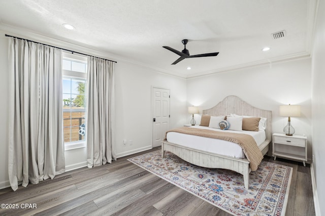 bedroom with baseboards, visible vents, ornamental molding, wood finished floors, and recessed lighting