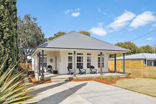 rear view of property with a porch, metal roof, and fence