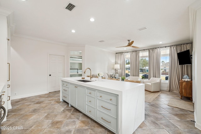 kitchen featuring visible vents, ornamental molding, open floor plan, a sink, and an island with sink