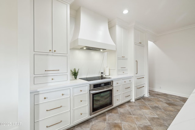 kitchen with white cabinets, custom range hood, black electric stovetop, light countertops, and stainless steel oven