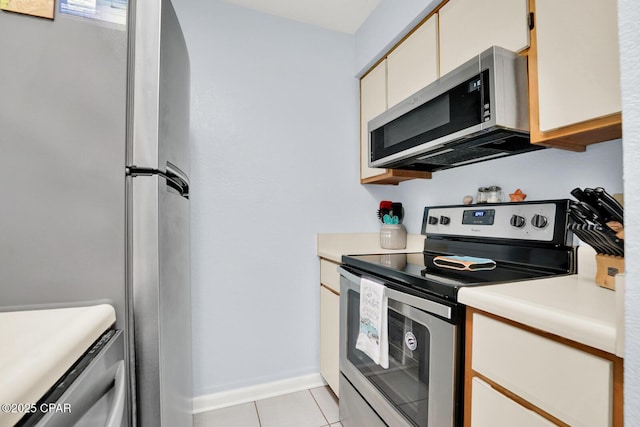 kitchen featuring light tile patterned floors, stainless steel appliances, light countertops, and baseboards